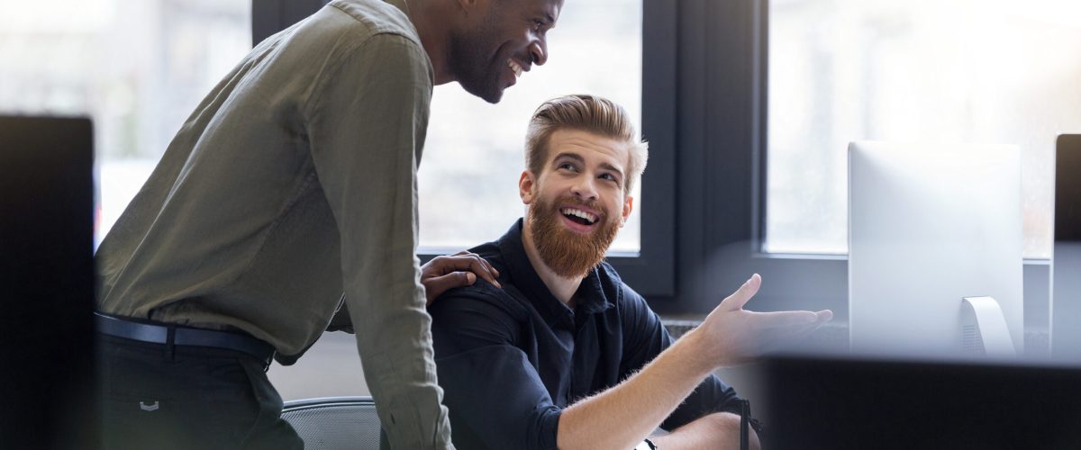 Two happy smiling men working together on a new business project at a workplace